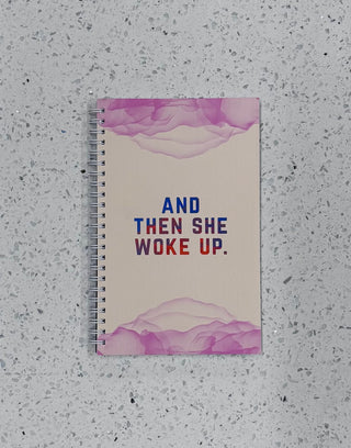 Notebook with 'And Then She Woke Up' text on a textured surface